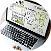 Escritorio con laptop mostrando wireframes y notas de mantenimiento web.