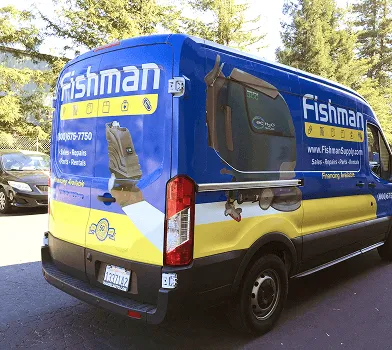 Van azul y amarilla con wrap de Fishman y fotos de pesca en la parte trasera.