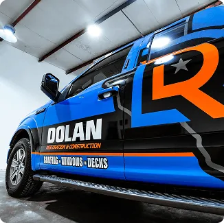 Detalle de van comercial azul con branding Dolan, gráfica naranja y negra en puertas.