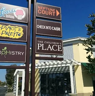 Tótem comercial con varios negocios junto a un centro comercial.