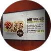 Menú de tacos impreso con fotos y precios sobre madera.