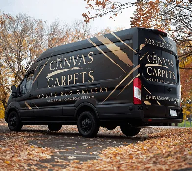 Van negra Canvas Carpets con letras doradas estacionada junto a árboles otoñales.