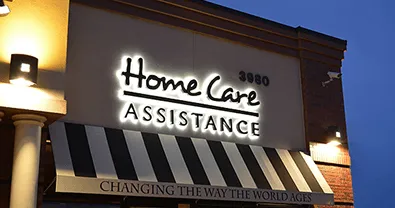 Letrero iluminado de 'Home Care Assistance' en fachada nocturna.