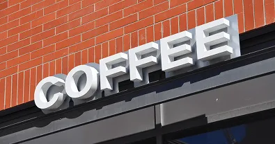 Letrero de letras corpóreas que dice 'COFFEE' en fachada de ladrillo.