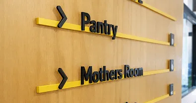 Señalización direccional interior con flechas y textos en pared de madera.