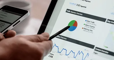 Persona señalando un dashboard de analítica en laptop con gráficas y reportes.